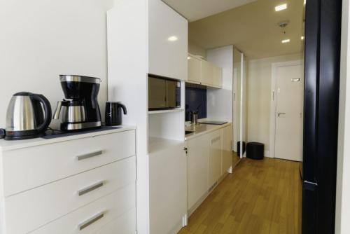 a kitchen with white cabinets and a microwave at PANORAMA view premium class rooms in Batumi