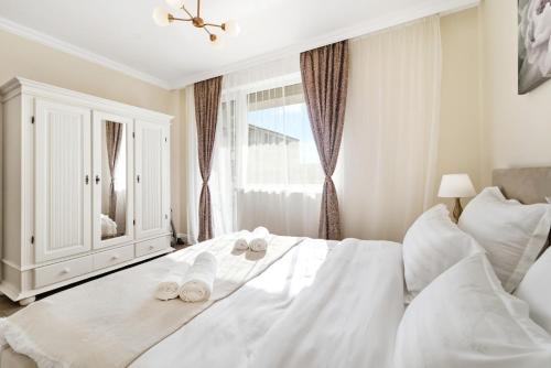 a bedroom with a white bed with slippers on it at Charming French Getaway Spacious Apartment with Garden and Parking in Dumbrăviţa