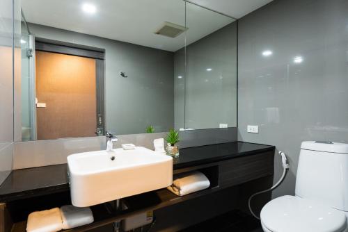 a bathroom with a sink and a toilet and a mirror at Fyn Hotel in Bangkok