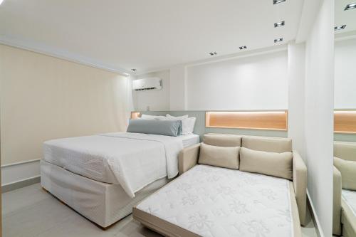 a white bedroom with a bed and a couch at Aurea Cabo Branco Beach in João Pessoa