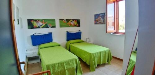 a room with two beds with green covers in it at La Dimora di Patty in San Cataldo