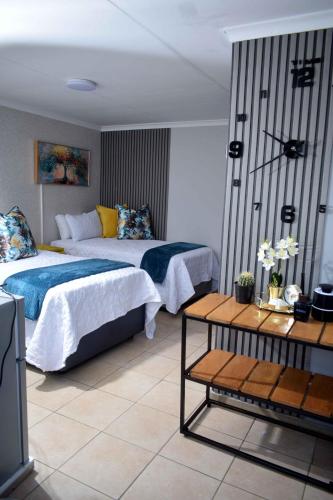 a hotel room with two beds and a table at Hlurile Lodge in Vosloorus
