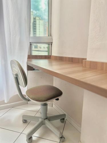 a desk and a chair in a room with a window at Apartamento completo no centro da cidade in Passo Fundo