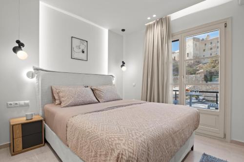a white bedroom with a bed and a window at Pnoe Luxe Apartment & Spa, Naxos Town in Naxos Chora