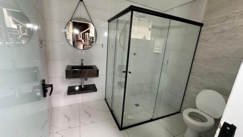 a bathroom with a glass shower and a toilet at Pousada Canto da Montanha in Guarujá