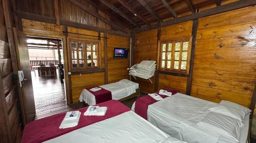 a room with three beds in a wooden cabin at Pousada Canto da Montanha in Guarujá