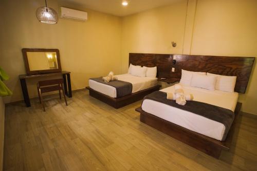 um quarto de hotel com duas camas e uma televisão em Hotel Boutique Bahia Azul em Bacalar