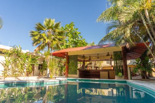 a swimming pool in front of a house with palm trees at Hotel Boutique Bahia Azul in Bacalar