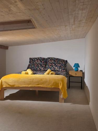 a bedroom with a bed with a yellow blanket and a table at Apartament nad belkami in Piece