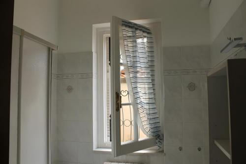 Lunigiana - Casa Anita Con Giardino في كاستيلنوفو ماغرا: حمام مع مرآة ونافذة مع مصراع