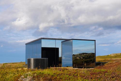 a glass building on top of a hill at Mirror Suite in Hjarðarholt