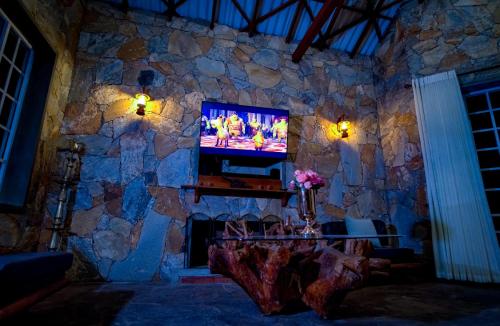 un soggiorno con parete in pietra e TV di The Colonial Crest a Nillambe