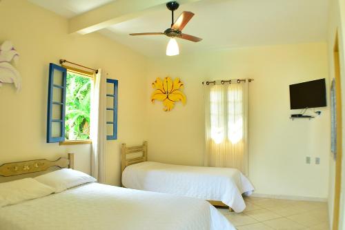 a bedroom with two beds and a ceiling fan at Pousada Recanto das Araras in Tiradentes