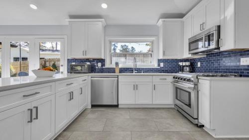 a white kitchen with white cabinets and appliances at Modern Villa Retreat in Historic College Park in Atlanta