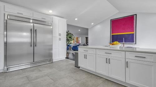 a kitchen with white cabinets and a stainless steel refrigerator at Modern Villa Retreat in Historic College Park in Atlanta
