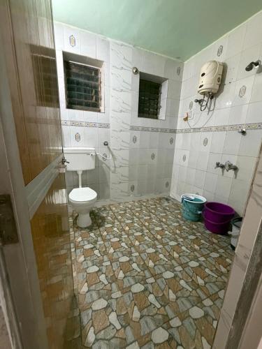 a bathroom with a toilet and a tiled floor at ShivSangit 2bhk Flat Homestay in Ponda