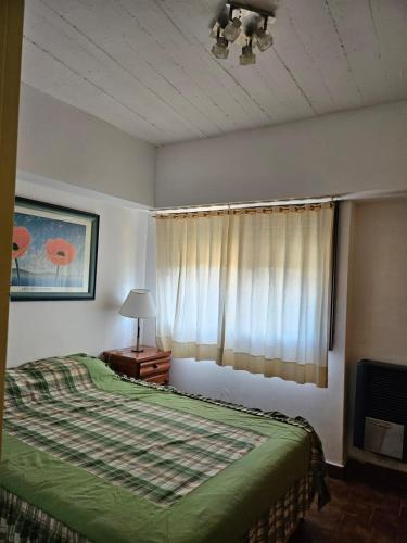 una camera da letto con un letto verde e una finestra di Departamento Villa Gesell 3 cuadras de la playa a Villa Gesell