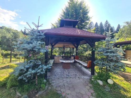 einen Pavillon mit einer Bank in einem Garten in der Unterkunft Max River Chalet in Porumbacu de Sus