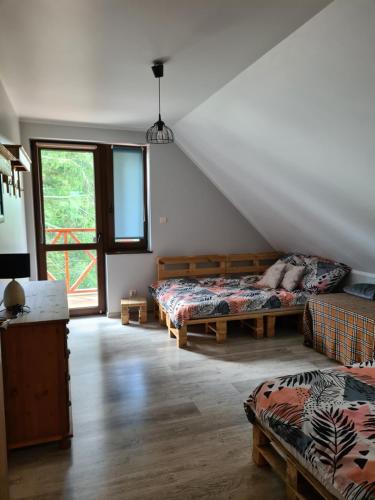 Skazdub StarySummer house in Suwalszczyzna- Dom w Dolinie Rospudy的有两张床和一扇窗户的阁楼房间
