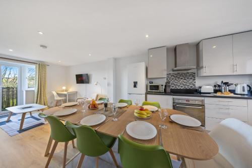 a kitchen and dining room with a wooden table and green chairs at Modern Hastings Home for Groups with Garden Terrace and Dedicated Workspace in Hastings