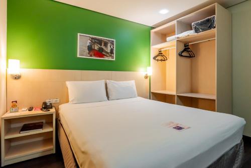 a bed in a room with a green wall at ibis Styles Belem Batista Campos in Belém