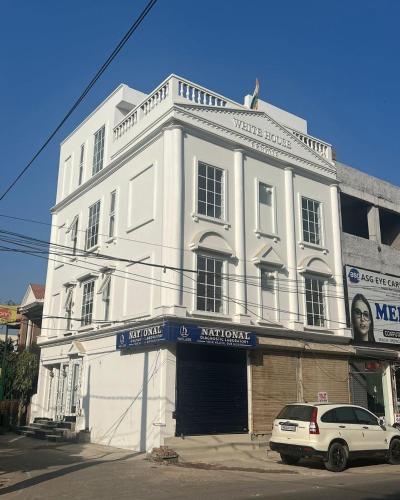 a white building with a car parked in front of it at Sky s whiye house in Ludhiana