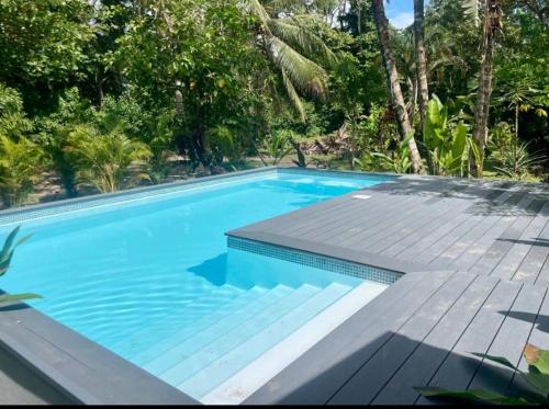 una piscina azul con una terraza de madera y árboles en Punta Uva Puerto Viejo Beach Front House with Swimming Pool, en Punta Uva