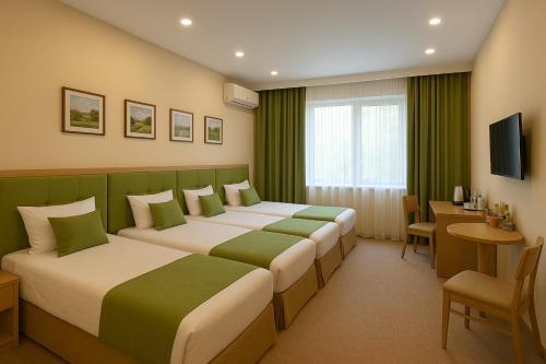 2 camas en una habitación de hotel con cortinas verdes en Khatai Deluxe Hotel, en Baku