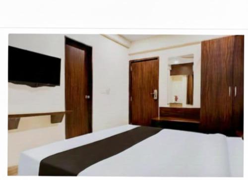 浦那Hotel Royal Inn的一间卧室，里面有一张床和一台平板电视