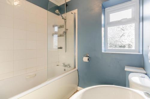 bagno con vasca, servizi igienici e finestra di 1 Pump Cottages a Theberton