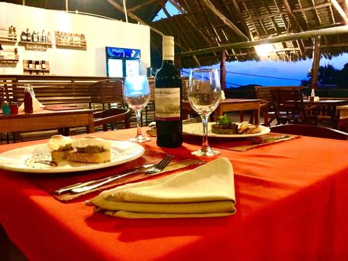 uma mesa com dois pratos de comida e uma garrafa de vinho em Jabulani House Rooms em Kendwa