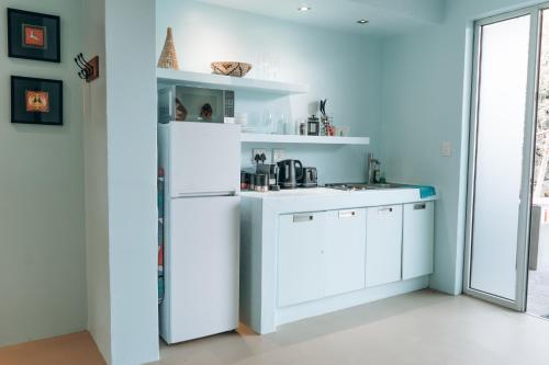 a kitchen with white cabinets and a white refrigerator at The Village Suites in Windhoek