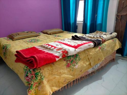 a bed with a red and white blanket on it at Kumbh Mela Vikas home stay in Prayagraj