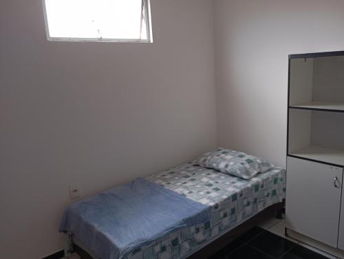 ein kleines Schlafzimmer mit einem Bett und einem Fenster in der Unterkunft Hospedagem próxima ao centro apto simples in Feira de Santana