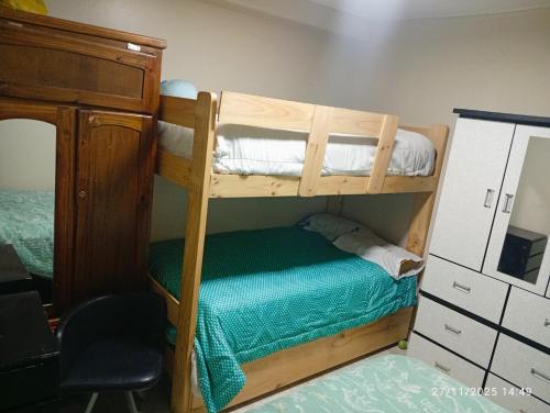 a bedroom with two bunk beds and a chair at Alojamiento colibrí in San Antonio