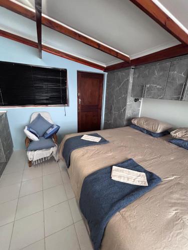 a bedroom with two beds and a chair at 52 Maroela street in Mossel Bay