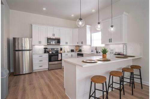 a kitchen with white cabinets and a kitchen island with stools at 5BR3BA Minutes from the Action with Skyline Views in San Antonio