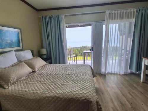 a bedroom with a bed and a view of a balcony at Jakaranda Holiday Flat in Uvongo Beach