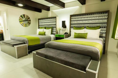 a bedroom with two beds and a bench in it at Baja Inn Hoteles Rio in Tijuana