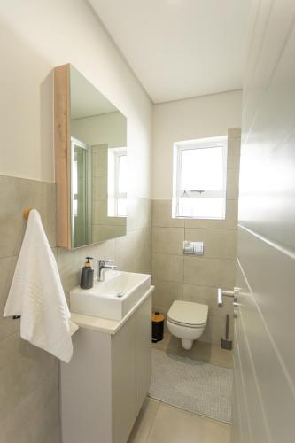 a bathroom with a sink and a toilet and a mirror at York Escape - Townhouse 26 in George