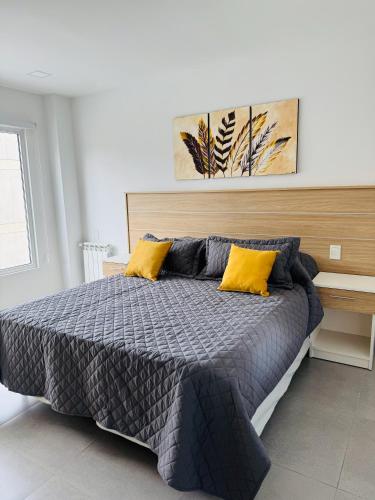 a bedroom with a bed with two yellow pillows at Gente del Sur - Avenida in Ushuaia