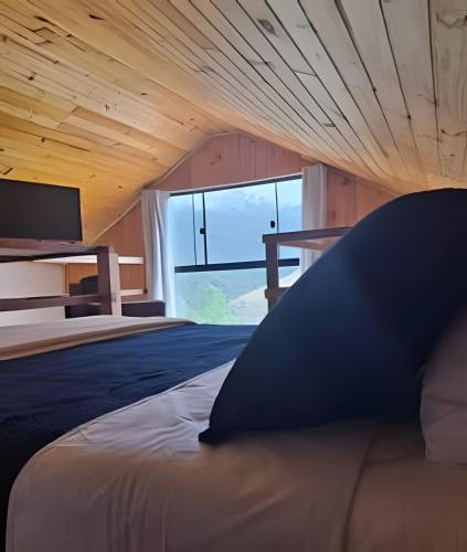 a bedroom with a large bed with a large window at Chalé com bela vista para as montanhas in Resende