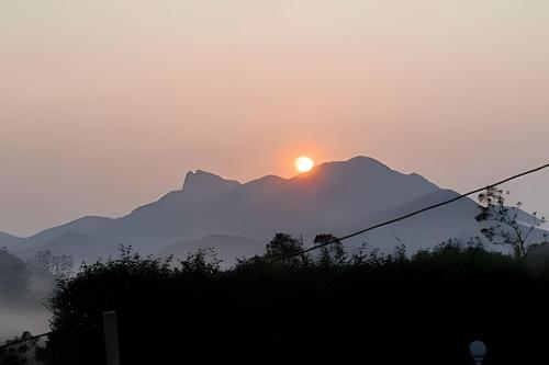 a sunset over a mountain range with the sun setting at Recanto dos Canários - CHALÉ 1 in Visconde De Maua