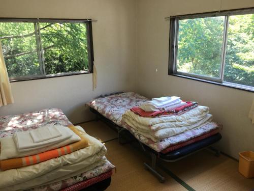 two twin beds in a room with two windows at Towadako Hostel in Towada