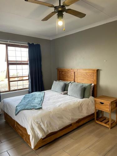 a bedroom with a large bed with a ceiling fan at Blossom on 13 in Gqeberha