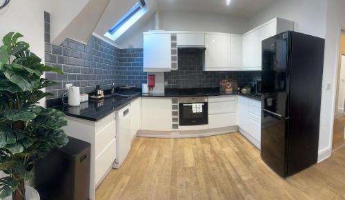 a kitchen with white cabinets and a black refrigerator at Gorgeous Town Centre 3-Bed 2-Bath Apartment Parking Available in Harrogate