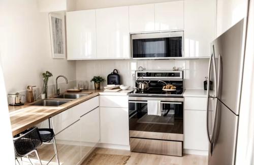 een keuken met witte kasten en een roestvrijstalen koelkast bij Amazing Beautiful Downtown Apt in Norfolk