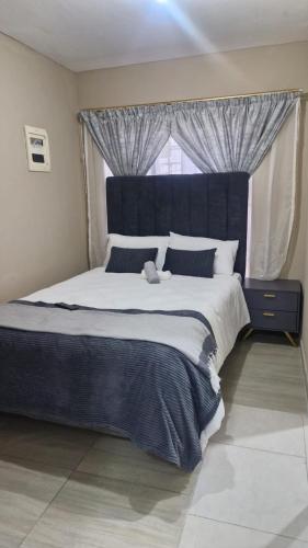 a bedroom with a large bed with a large window at Nkwe Guesthouse in Roodepoort