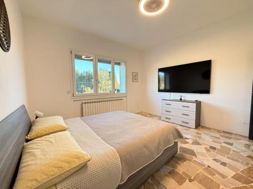 a bedroom with a large bed and a flat screen tv at Family 3-Bedroom Apartment near MXP & Lake Maggiore - Parking in Sesto Calende