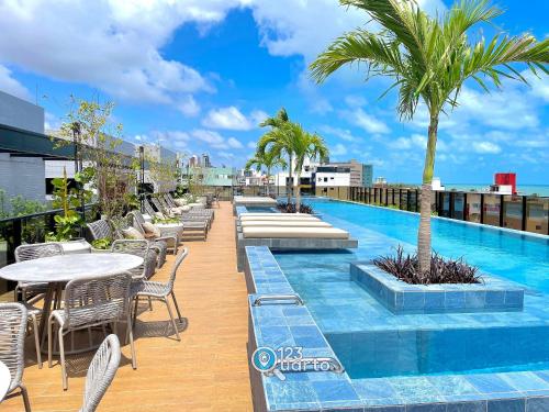 uma piscina no telhado de um edifício com mesas e cadeiras em Hit Cabo Branco by 123Quarto em Tambaú